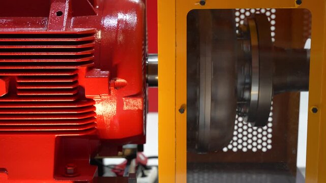 Industrial electric motor and flexible shaft coupling behind yellow safety guard
