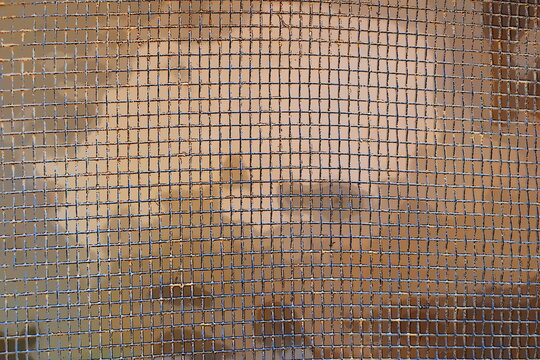Rusty metal wire mesh screen with square grid pattern in blue and brown tones