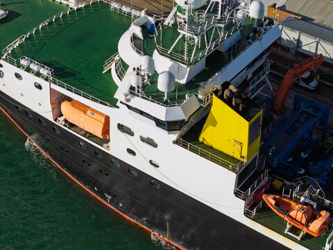 Aerial view of a research vessel with a yellow funnel, lifeboats, and radar equipment on deck sailing in the sea, United Kingdom.