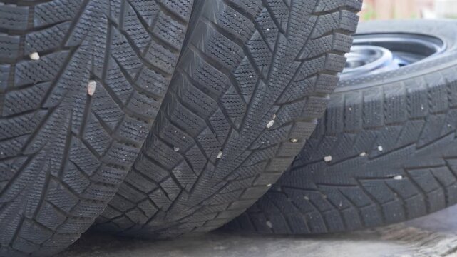 Group of tires stacked with deep grooves underlines safety. Autumn is reminder to switch sets. Winter tread pattern preserves vehicle stability in frost and snow