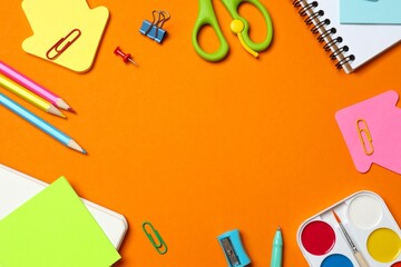 Flat lay with notebook and school stationery on orange background, copy space © Sunlight