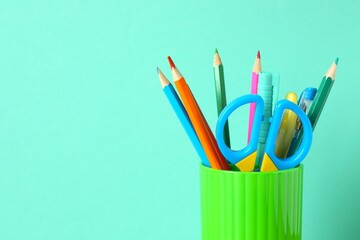 Close-up view of green pencil holder filled with colorful school supplies on color surface © Sunlight