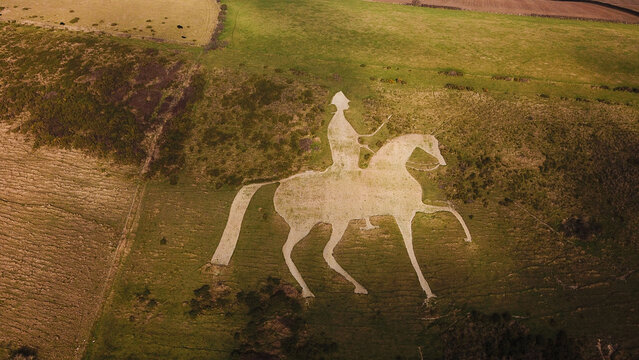 Aerial view of the Osmington White Horse hill figure carved into the chalk hillside, surrounded by grassy fields in Weymouth, England, United Kingdom.