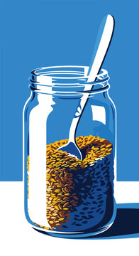 A spoon is submerged in a glass jar filled with seeds