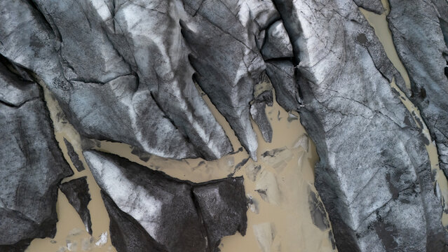 Aerial view of Iceland Glaciers showing deep crevasses, jagged ice formations, and sediment-rich meltwater streams in Vik, Myrdalshreppur, Iceland.