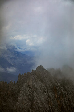 Aerial view of the rugged limestone peaks of the Nordkette mountains partially obscured by thick clouds in Innsbruck, Tyrol, Austria.