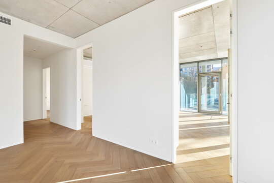 Modern empty apartment interior mockup with open layout, white walls, and bare concrete ceiling.