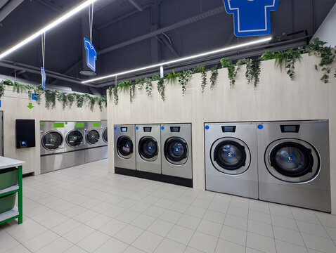 Modern self service laundromat with rows of washing machines and dryers