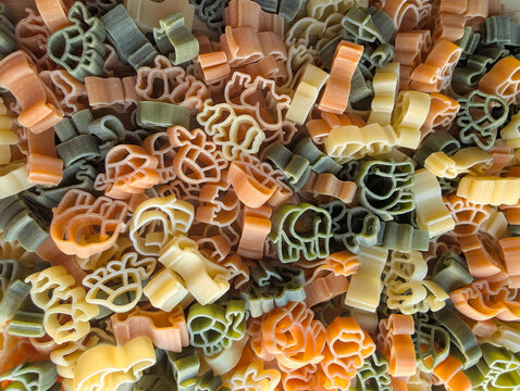 Top view of colorful uncooked animal shaped pasta texture background