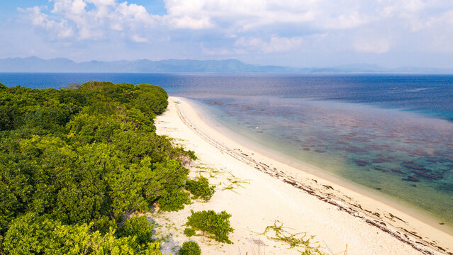 Aerial view of a pristine white sand beach bordered by lush tropical forest and clear turquoise waters in Busuanga, Mimaropa, Philippines.
