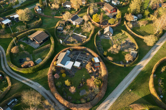 Aerial view of The Round Gardens of Naerum, featuring unique oval-shaped hedges surrounding individual houses and gardens, with lush green lawns and pathways in Naerum, Denmark.