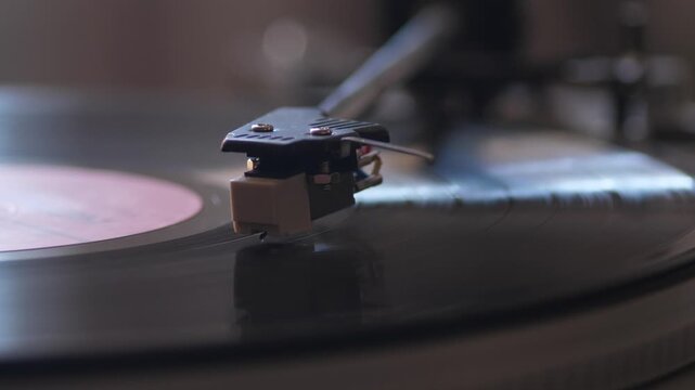A vintage vinyl record player spins a classic LP while the tone arm and stylus track the audio grooves. This nostalgic close-up view captures the warm, high-fidelity sound of analog music playback