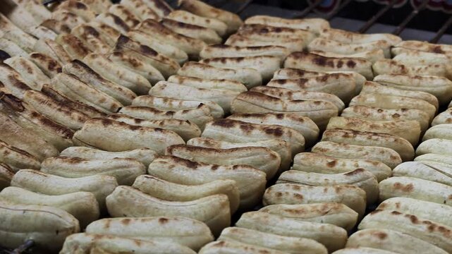 Camera Panning Across Skewered Bananas Grilling Over Heat at Asian Night Market