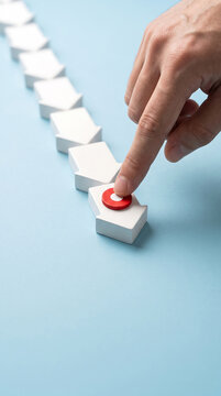 Person pressing red button on white block in sequential line set