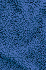 Detailed texture of dark blue sherpa fleece fabric. Top view close-up of soft curly textile material for outerwear and interior design softly draped to create an abstract background © DariaR