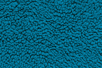 A full-frame, detailed close-up shot of deep blue sherpa fleece fabric, showing a fuzzy, curly teddy bear texture from a top-down view. Concept of warmth, winter comfort, cozy textile © DariaR