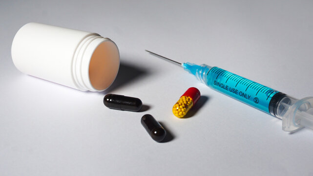 Capsules, medical bottle and a syringe contain blue liquid. Medication concept. 