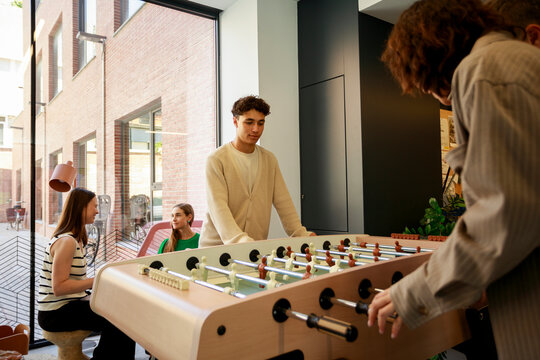 Friends Play Foosball at a office hallway