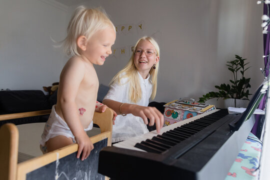 Teenage girl and her little sister play the electric piano