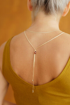 Delicate gold necklace draped across a woman&rsquo;s bare back