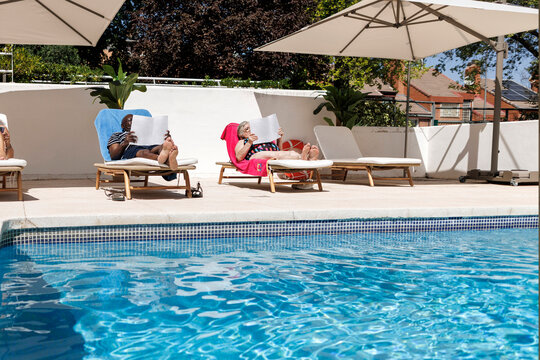 Mature people relaxing poolside enjoying sunny vacation