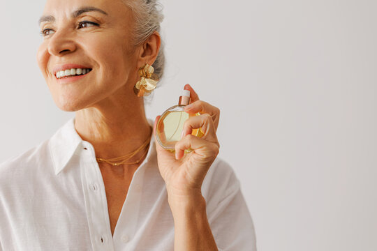 Mature woman applying luxury fragrance feeling fresh and beautiful