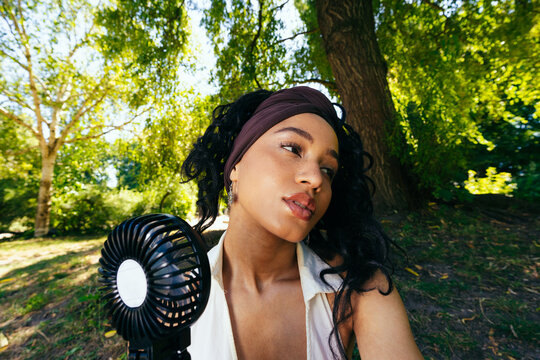 Woman Using Fan in Park Heatwave