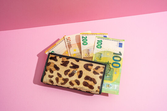Leopard print wallet with euro banknotes on pink background