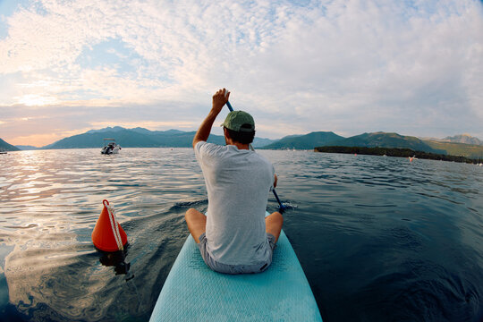 Man Paddles on a Blue Paddleboard sunset