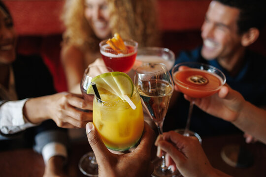 Friends celebrating and toasting with cocktails at a bar