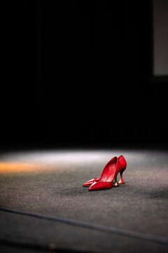 Elegant red high heels shoes standing on an empty stage under a spotlight. Concept of fashion, performance and celebrity.