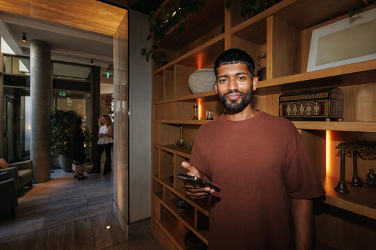 Young man holding smartphone in modern hotel lounge