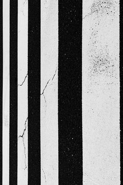 Abstract black and white zebra crossing close-up with cracked asphalt texture and bold vertical stripes