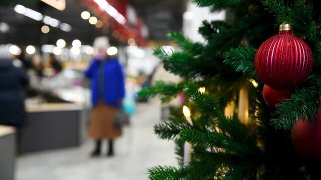 Close-up of a Christmas tree decorated with colorful balls and garlands in a shopping mall or store.
