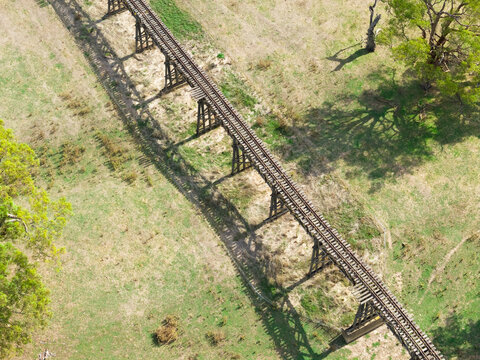 Abandoned railway bridge casting a shadow over farmland below
