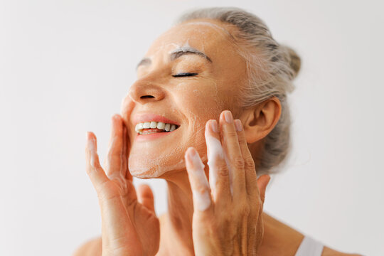 Senior woman enjoying daily skincare routine with cleanser