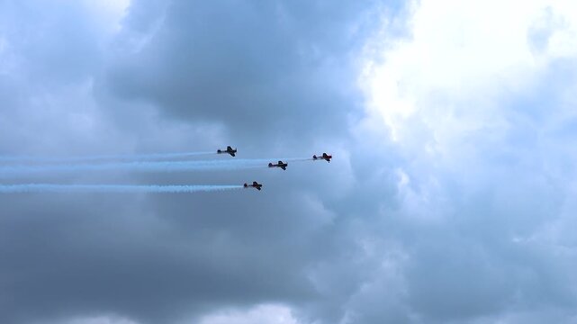 Sports planes fly in formation with smoke trails.