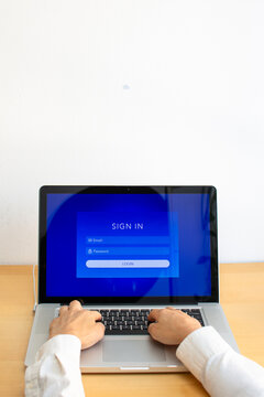 Vertical front view of hands typing on laptop screen showing sign in login interface on desk