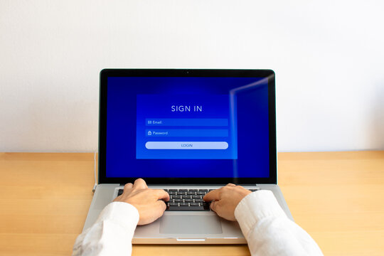 Front view of person typing on laptop keyboard displaying sign in login page on screen