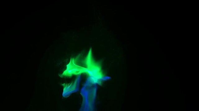 Blue and green smoke curls into a skull shape, shifting against a black background