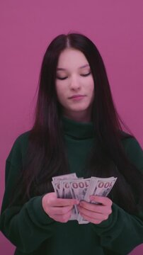 Girl is holding dollar bills in her hands. Woman has a stack of money. Ecstatic teen girl rejoicing success and holding lots of cash. Portrait young female with banknote