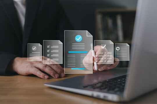 Businessman using stylus on laptop with digital document icons, representing document management system, online approval, paperless office, and compliance check.