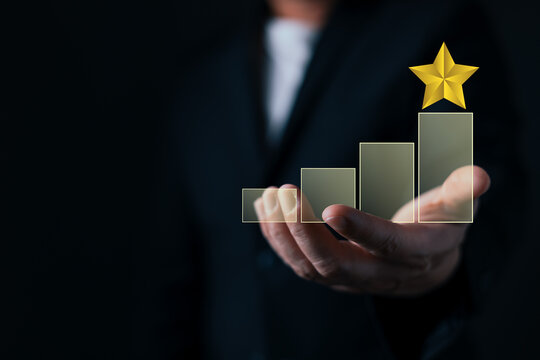 Businessman holding rising growth bar chart with a golden star, representing financial success, business development, and best performance.