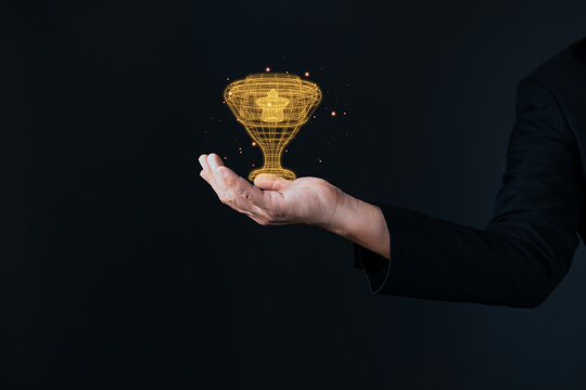 Businessman holding glowing golden trophy wireframe, representing victory, business achievement, leadership, and successful award recognition.