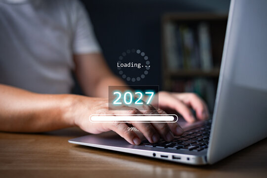 Man working on laptop with loading progress bar to year 2027, representing future planning, digital business transition, countdown technology, and new targets.
