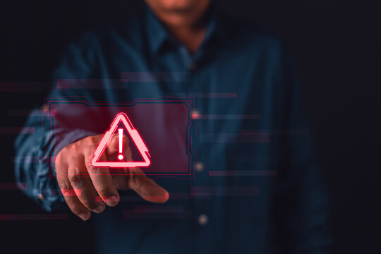 Businessman touching red glowing warning icon on digital screen, representing cybersecurity threat, risk management, and system error alert. symbolizing caution and threats.