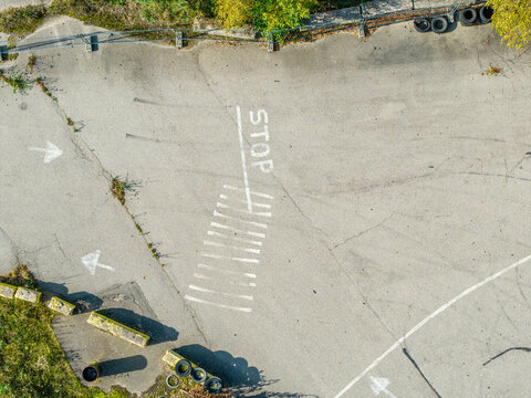Aerial view of a paved drift track section featuring a painted stop sign, directional arrows, and tire marks on the asphalt surface in Krimulda Parish, Sigulda Municipality, Latvia.