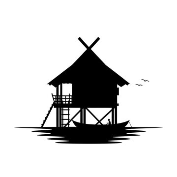 Traditional stilt house silhouette over water with small boat