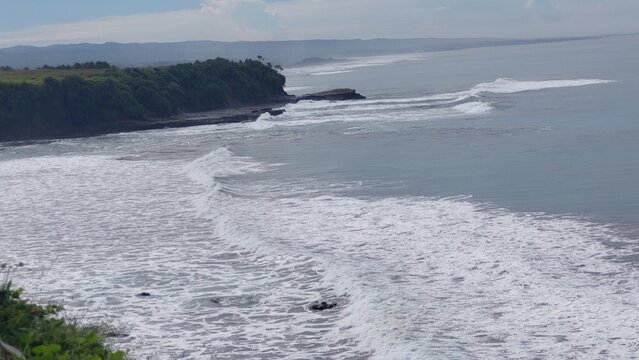 Scenic view of powerful ocean waves crashing on a sandy beach along the coastline