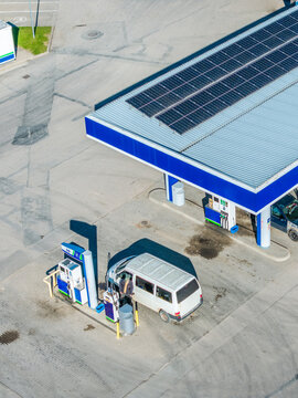Aerial view of a gas station with solar panels on the roof and a white van refueling at the pumps in Ragana, Sigulda Municipality, Latvia.